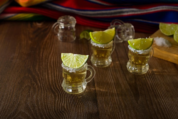 Tequila shots with salt and lime on a bar table Shots of tequila and typical mexican elements