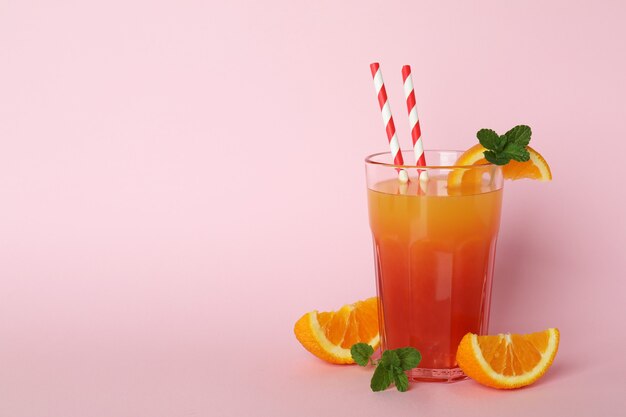 Tequila sunrise cocktail and ingredients on pink background