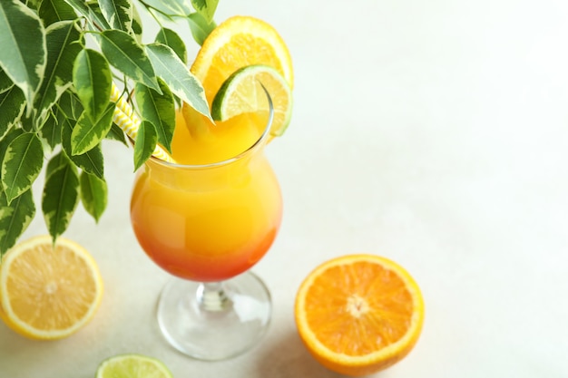 Tequila sunrise cocktail and ingredients on white textured table