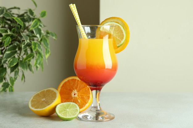 Tequila sunrise cocktail and ingredients on white textured table