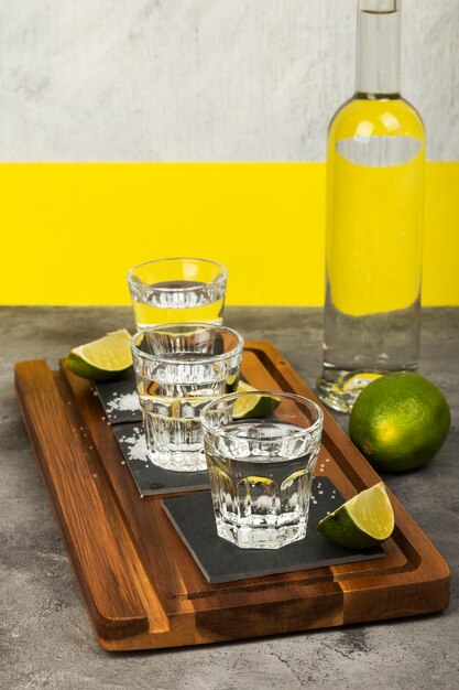 Tequilafles en schoten met limoenen en zout op houten raad