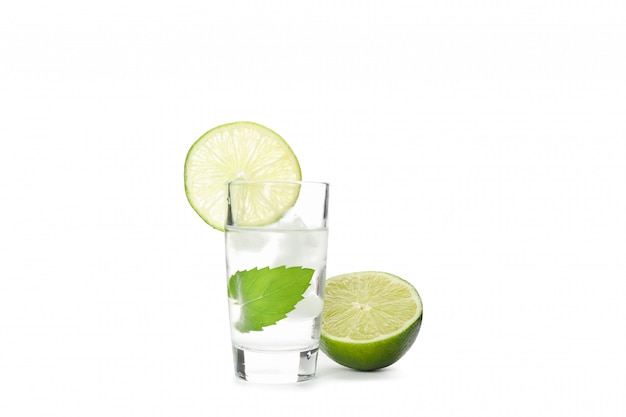 Tequilaschot met kalk, munt en ijs dat op wit wordt geïsoleerd