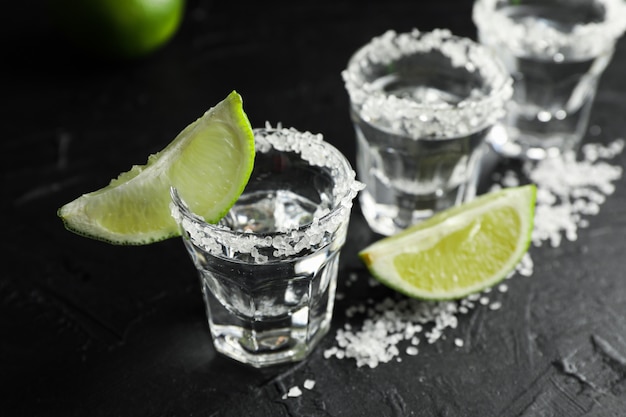 Tequilaschoten met plakjes zout en limoen op zwart