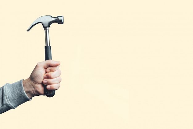 Ter beschikking geïsoleerde hamer. Mens die een uitstekende hamer, hulpmiddel in de hand houdt.