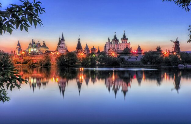 Teremki van het Izmailovsky Kremlin in Moskou met weerspiegeling in het water van de vijver in het licht van de avondlichten