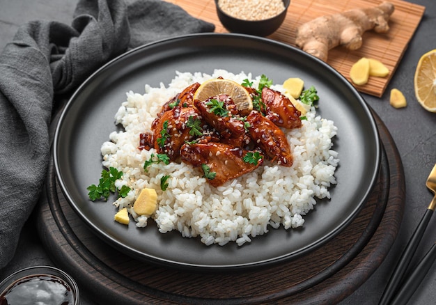 Teriyaki chicken with rice, sesame and ginger on a dark background. Side view, close-up. Japanese cuisine.