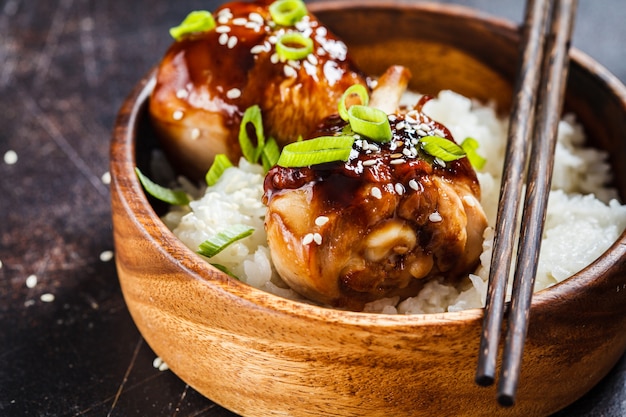 Teriyaki chicken with white rice in a wooden bowl.