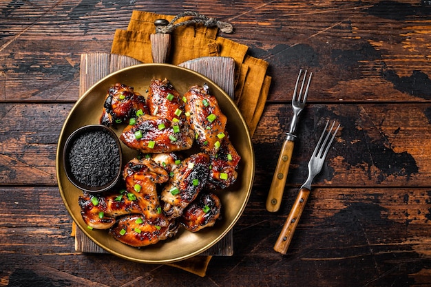 Teriyaki kippenvleugels met zwarte sesam op een bord Houten achtergrond Topweergave