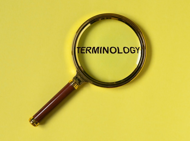 Terminology word through magnifier on bright yellow background top view