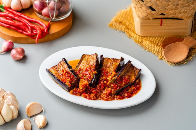 Terong Balado or eggplant with sambal balado Serving in white plate on gray background