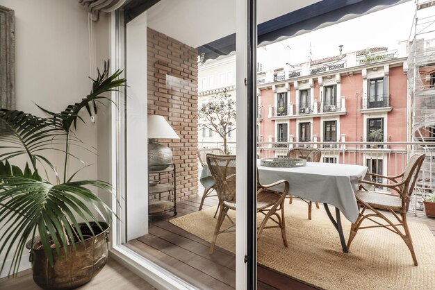 Terrace of a residential house in a vintage building with acacia wood plank flooring with a cane table and chairs a jute rug