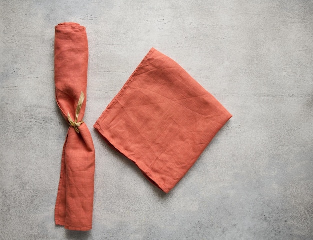 Terracotta folded linen napkins on gray concrete table with copy space top view