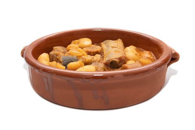 A terracotta plate with Asturian fabada a typical Spanish bean stew on a white background