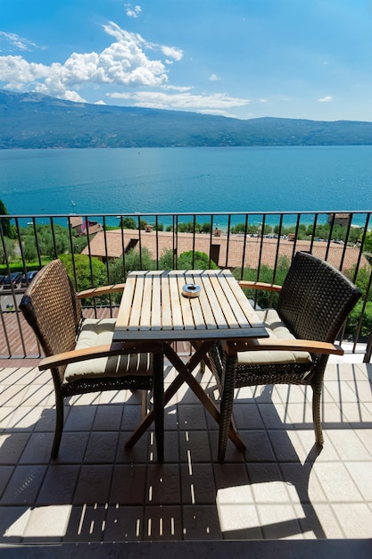 Terras met tafel en stoelen met uitzicht op het Gardameer in Gargnano in Italië. Veranda bij café of restaurantconcept. Vakantie zomer ontwerp. Balkonmening in modern woonflatflat of hotel.