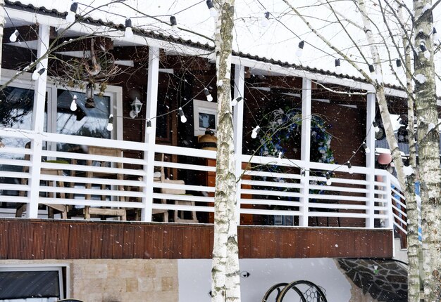 Terras van een houten huis met twee verdiepingen met uitzicht op het winterbos