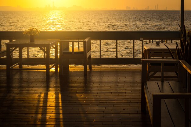 Foto terras zeezicht met stoelen en tafel bij zonsopgang