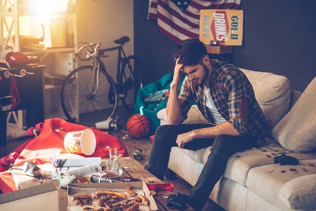 Terrible hangover. Frustrated young man keeping hand in hair 