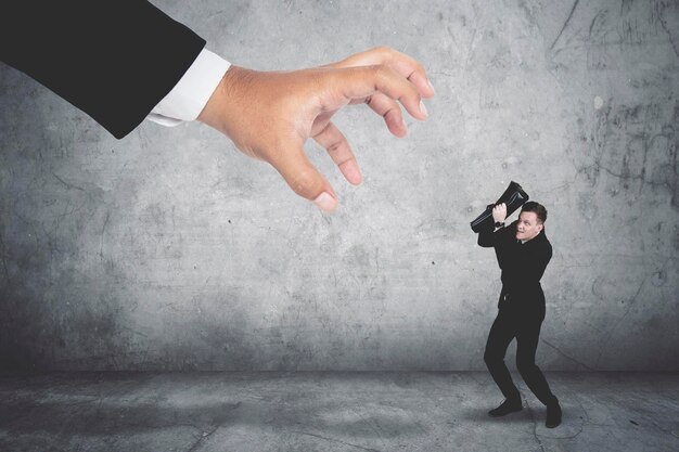 Terrifying businessman covering his face being attacked by a giant hand