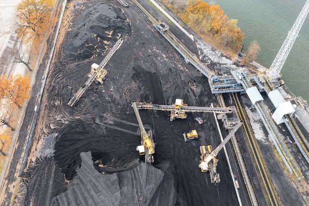 Territory of the coal terminal with coal dumps and a regenerator loading and unloading of coal by excavators and belt conveyors coal reserves at thermal power plants View from above