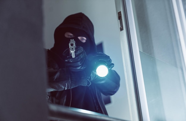 Terrorist or a Burglar pointing with a gun outside a window at night