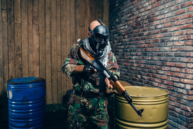 Terrorist in gas mask with kalashnikov rifle, male mujahedin with weapon.