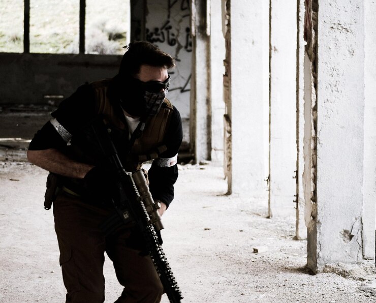 Photo terrorist with gun standing by wall