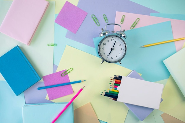 Terug naar school briefpapier wekker stapel boeken papier en gekleurde potloden