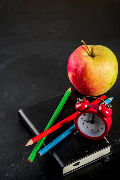 Terug naar school concept met boeken wekker kleur potloden schoolbord achtergrond