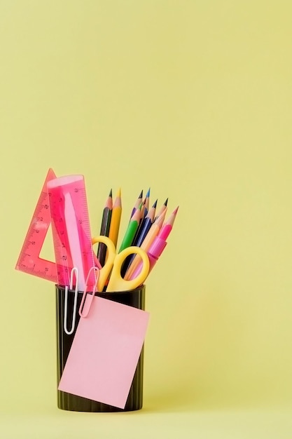 Terug naar school concept met ruimte voor tekst kopieer ruimte school kantoorbenodigdhedencreatief bureau met kleurrijke briefpapier gekleurde paperclipschoolbenodigdheden op gele achtergrondbureau