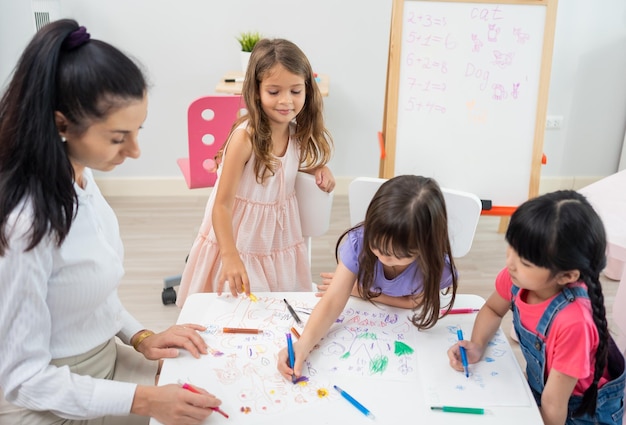 Terug naar school en zomercursus. Kleuterjuf met kinderen tekenen en kleuren.