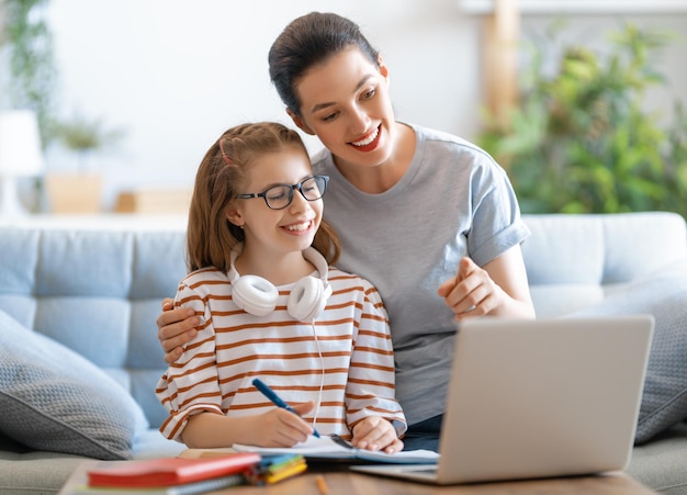 Terug naar school. Gelukkig kind en volwassene zitten aan de balie. Meisje huiswerk of online onderwijs.