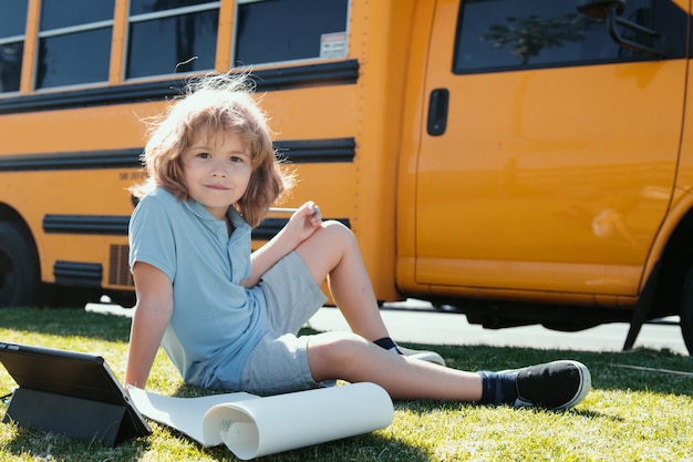 Terug naar school gelukkig kind studeren in park in de buurt van schoolbus schooljongen huiswerk of online educatie