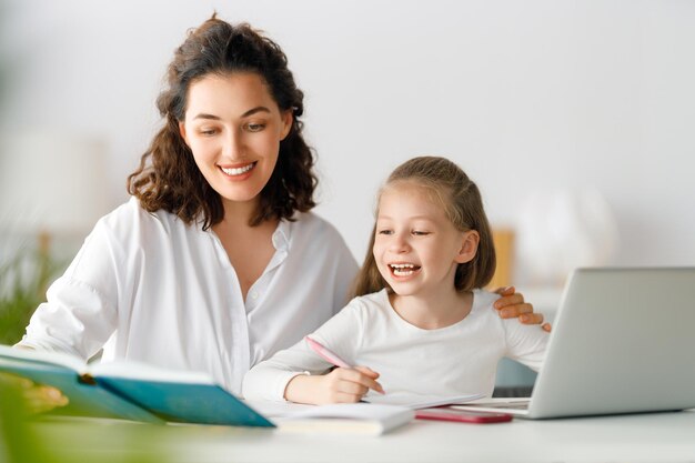 Terug naar school Gelukkige kind en volwassene zitten aan het bureau Meisje doet huiswerk of online onderwijs