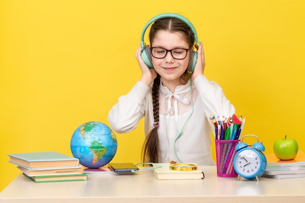 Terug naar school Het schoolmeisje zit aan het bureau en luistert naar muziek