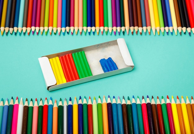 Terug naar school. Kleurenpotloden en boetseerklei op blauwe achtergrond