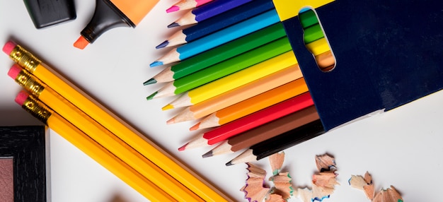 terug naar school, kleurpotloden en een roze stift op een witte tafel