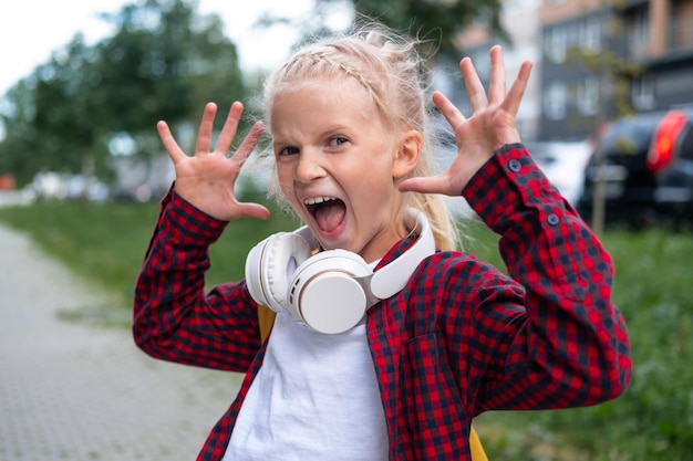 Terug naar school Opgewonden blij meisje met gele rugzakken spelen op straat in de buurt van school na pandemie over studenten zijn klaar voor het nieuwe jaar