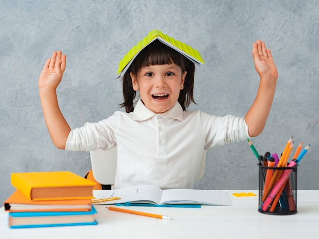 Terug naar school. Schattig kind schoolmeisje zit aan een bureau in een kamer.