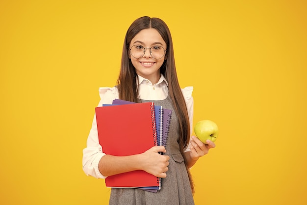 Terug naar school School kind tiener student meisje met rugzak houden appel en boek geïsoleerd op geel