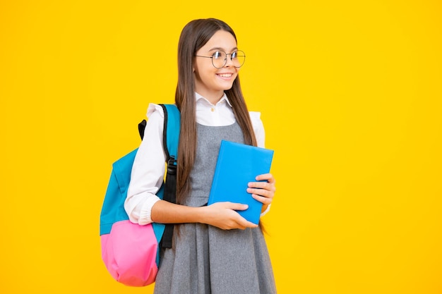 Terug naar school Schoolmeisje student houdt boek op gele geïsoleerde studio achtergrond School en onderwijs concept tiener meisje in schooluniform