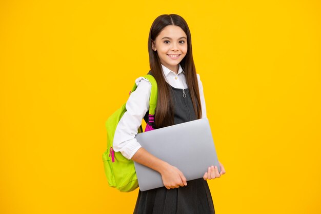 Terug naar school Tiener schoolmeisje houdt notebook laptop Schoolkinderen op geïsoleerde gele studio