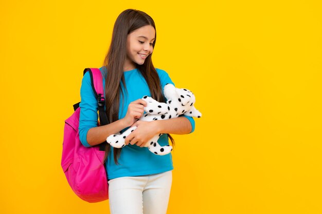 Terug naar school Tiener schoolmeisje houdt speelgoed Schoolkinderen met favoriete speelgoed op geïsoleerde gele studio achtergrond Gelukkig tiener portret Lachende girl