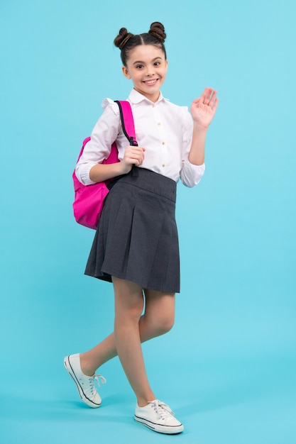 Terug naar school Tienerschoolmeisje in schooluniform met zak 1 september kennisdag Schoolkinderen op blauwe geïsoleerde studioachtergrond