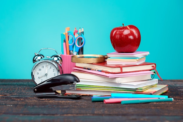 Terug naar schoolconcept. Boeken, kleurpotloden en klok op blauwe achtergrond