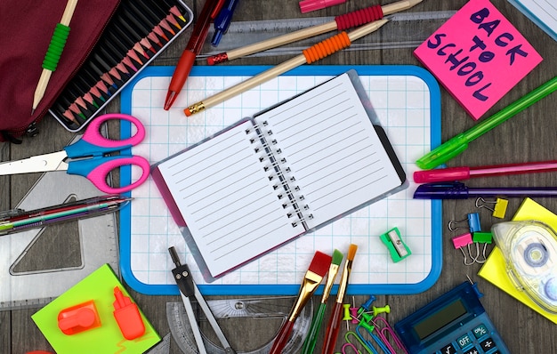 Foto terug naar schoolconcept: bureau en schoollevering met een notitieboekje op een houten achtergrond