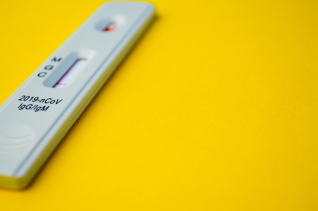 Il test per il coronavirus si trova su uno sfondo giallo una goccia di sangue su una diagnosi rapida della striscia reattiva