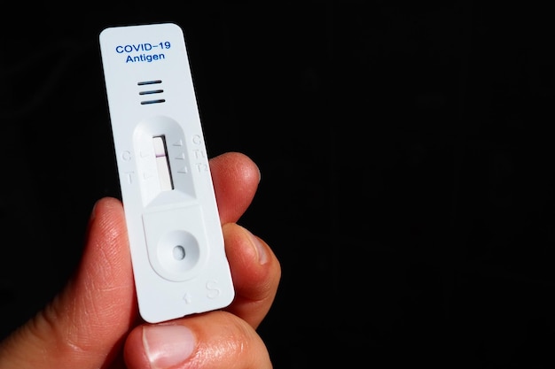 The test result for COVID-19 is negative, not infected, using rapid testing equipment. Test for coronavirus on the hand, black background. Copy space. Testing Concept Coronavirus Disease infection.