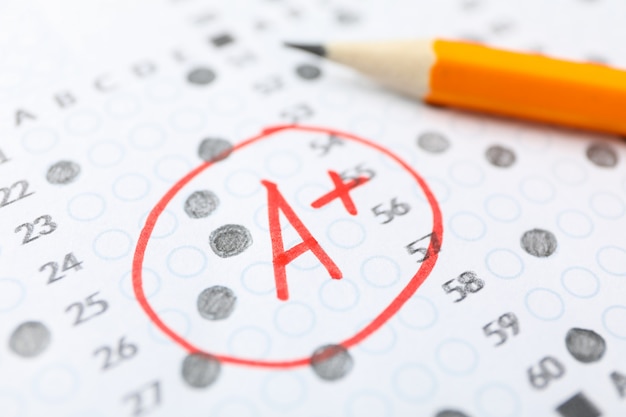 Test score sheet with answers, grade A+ and pencil, close up