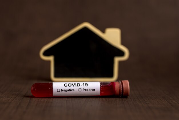 A test tube filled with a blood sample for testing with house shape black board.