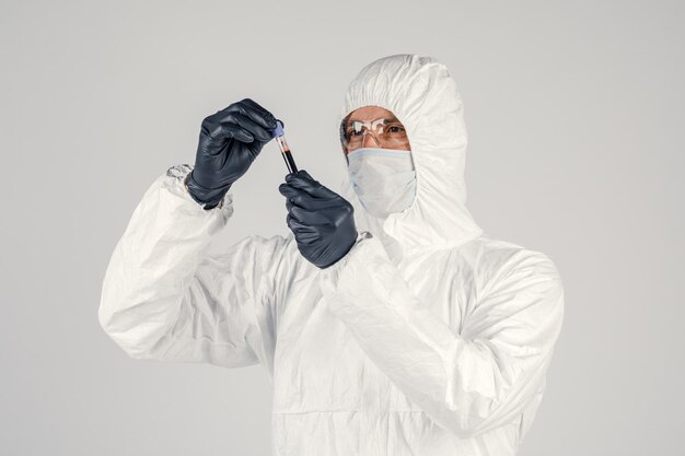 A test tube in a man's hand closeup a man in a medical mask holding a bottle of red liquid Concept of blood samples medical and chemical research